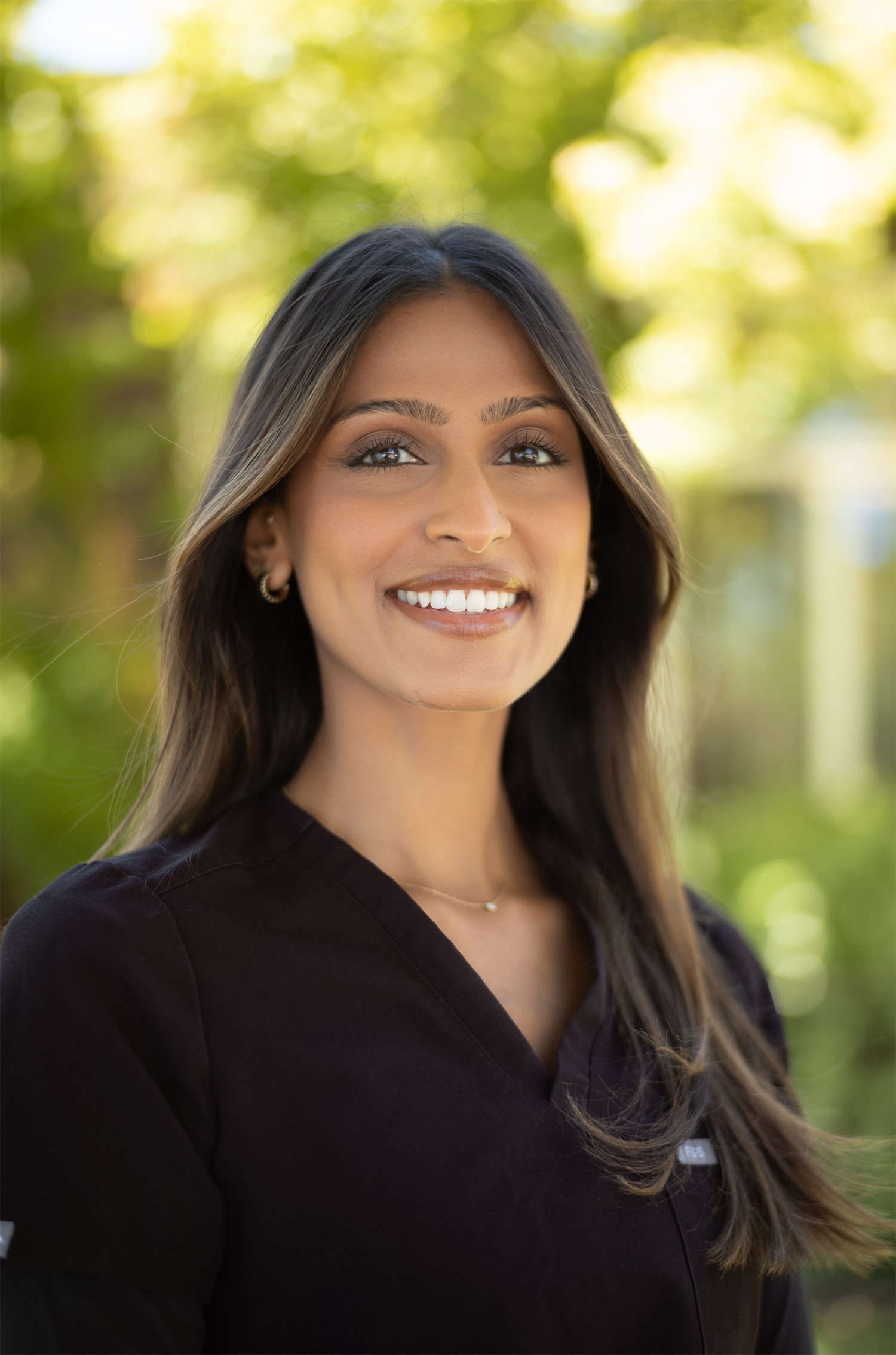 Smiling woman with wavy blonde hair holding a hand mirror, examining her teeth.