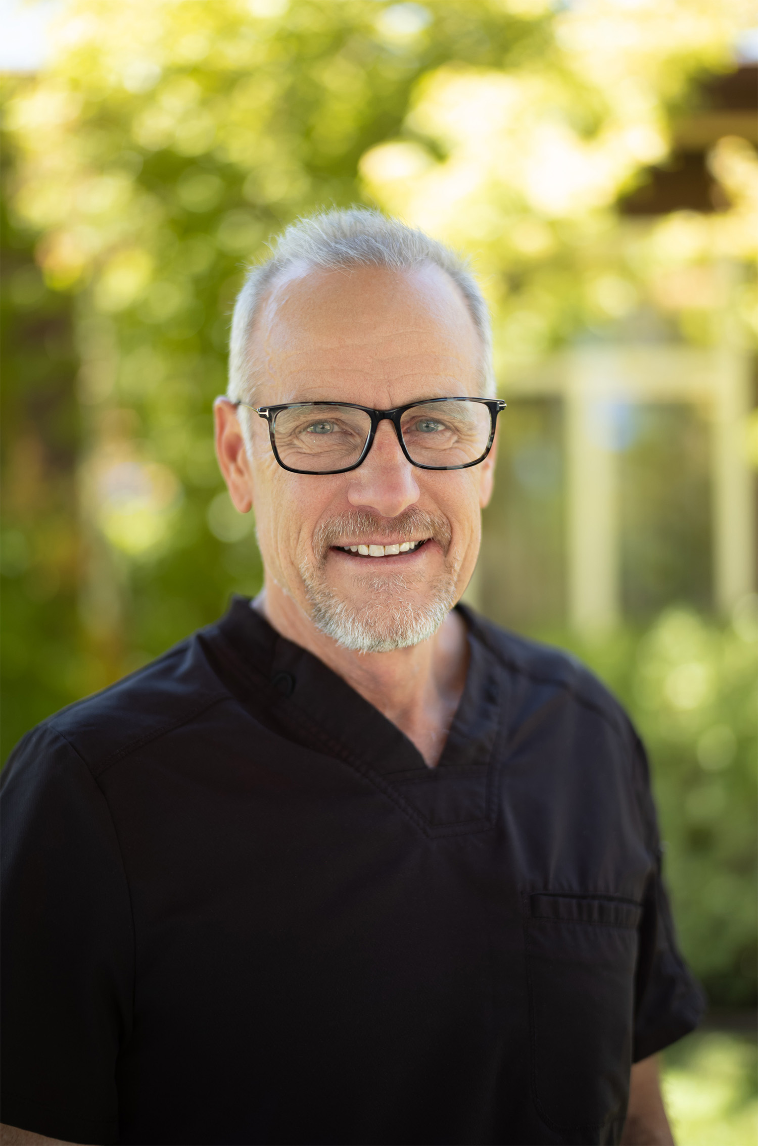 Smiling woman with wavy blonde hair holding a hand mirror, examining her teeth.