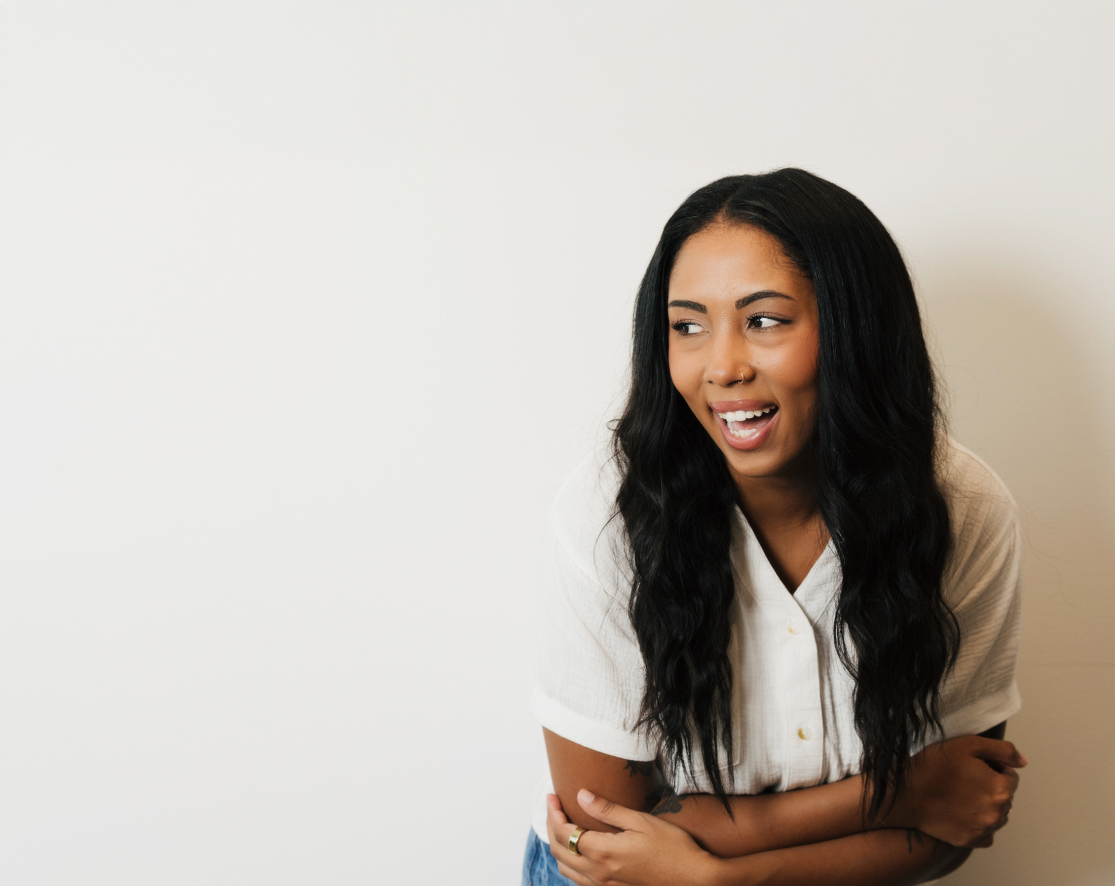Rocky coastline with cliffs and waves crashing into a small sandy beach beneath a cloudy sky.