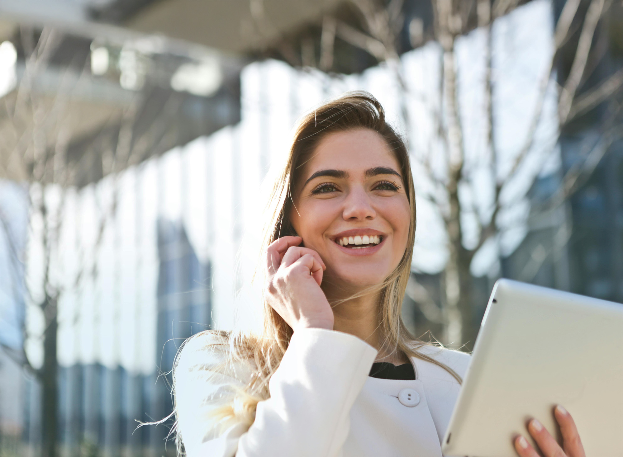 Rocky coastline with cliffs and waves crashing into a small sandy beach beneath a cloudy sky.