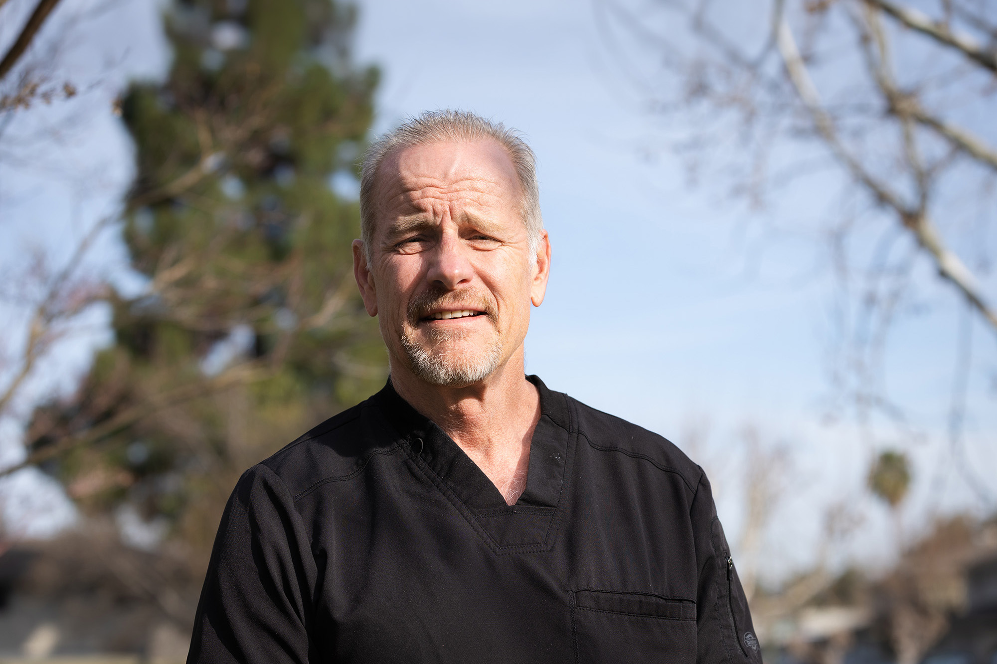 Smiling woman with wavy blonde hair holding a hand mirror, examining her teeth.