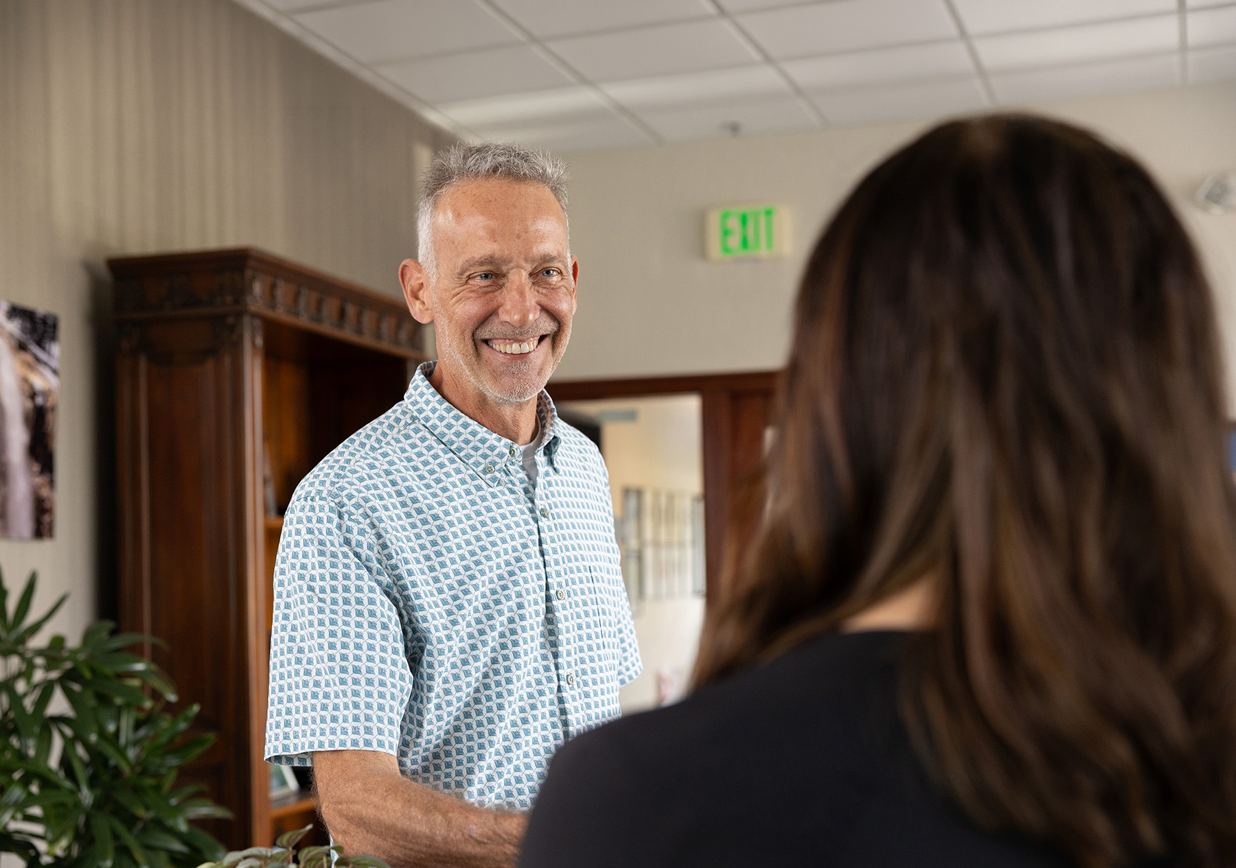 Rocky coastline with cliffs and waves crashing into a small sandy beach beneath a cloudy sky.
