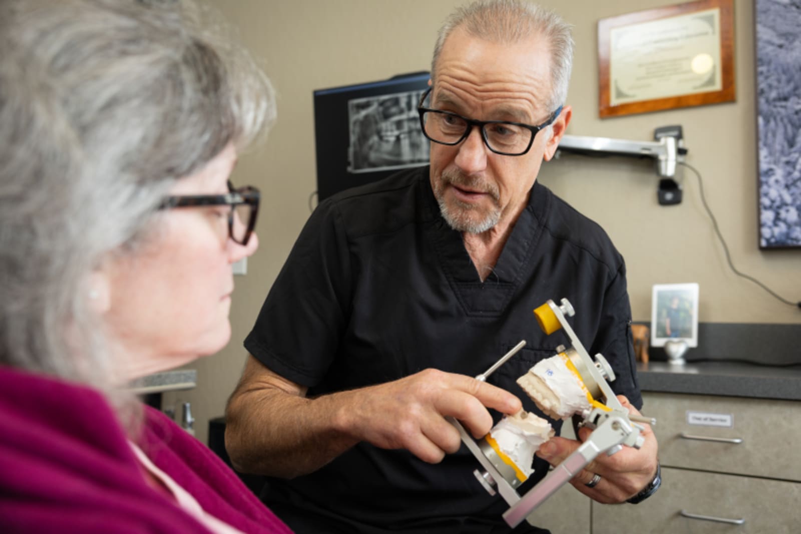 Dentist discussing dental model with patient in treatment room