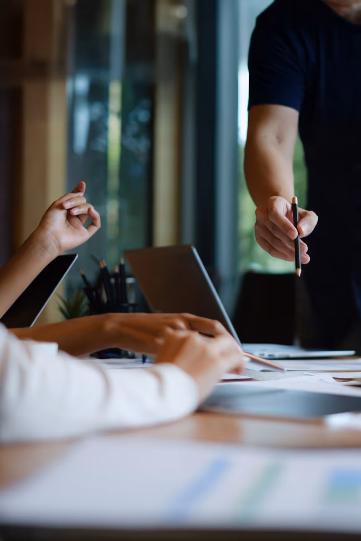 Close-up of hands during a business meeting with laptops and documents on the table.
