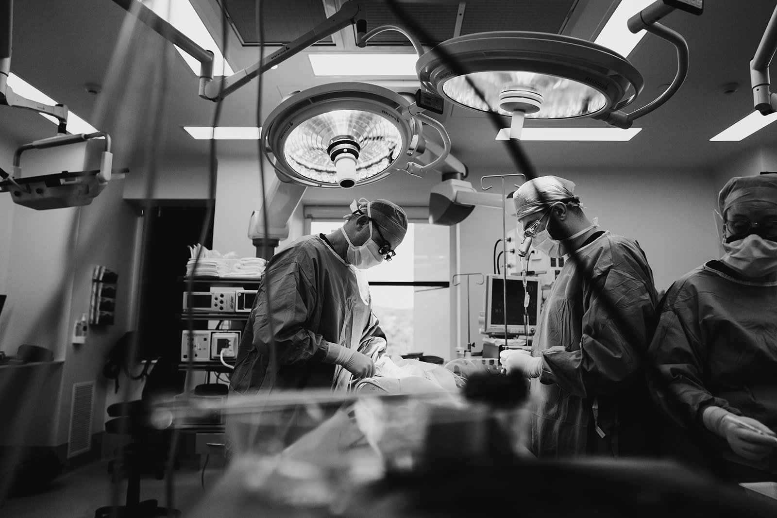 Black and white photo of a surgical team performing an operation in a well-lit operating room.