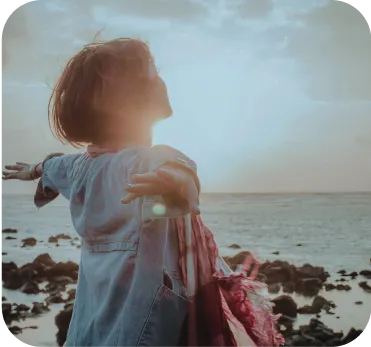 Business Setup in Dubai: Entrepreneur embracing freedom by rocky seaside at sunset