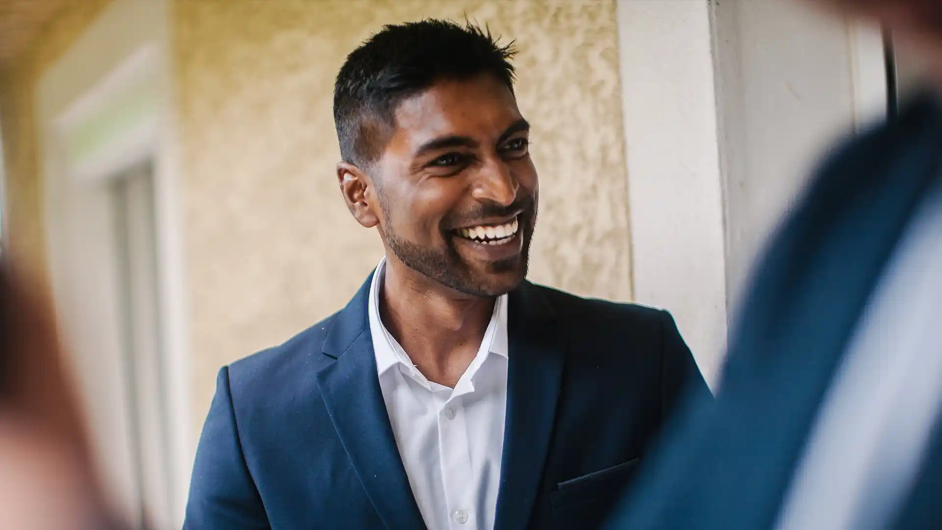 Indian man in blue coat smiling talking to people