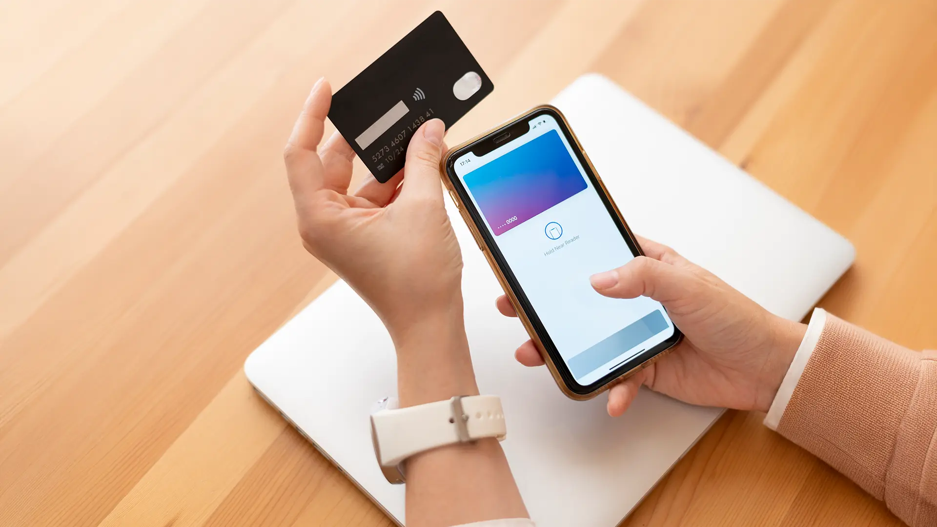 Person using a smartphone for online banking with a debit card, representing salary transfer account options in Dubai