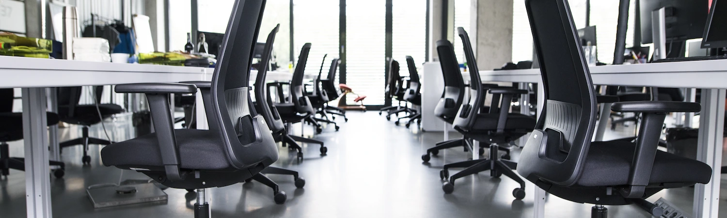Rows of empty desks and office chairs in a vacated office