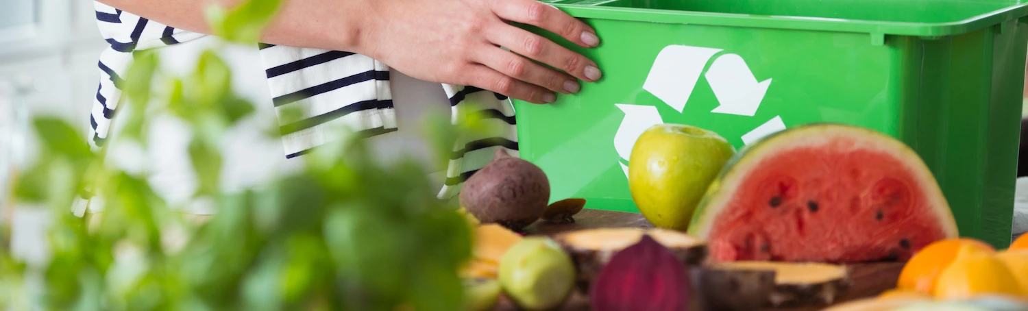 Food scraps being placed into a green organics recycling bin