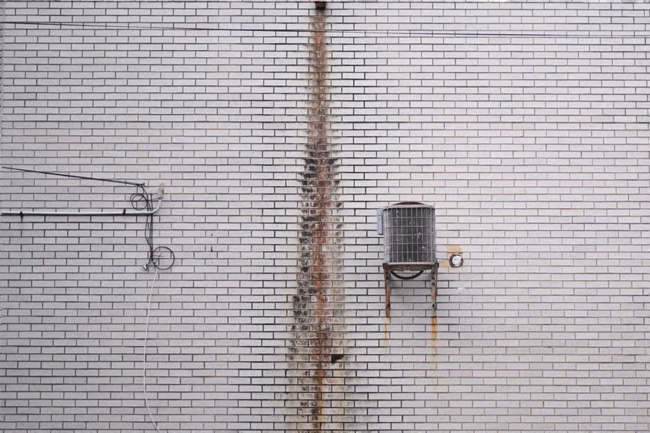 An aging outdoor condenser unit with rusted fins and worn electrical whip An aging outdoor condenser unit with rusted fins and worn electrical whip