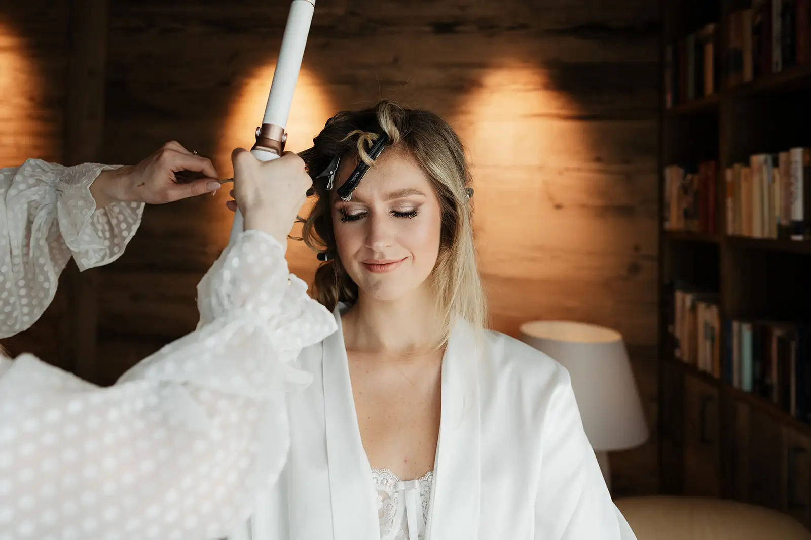 Hochzeit Getting ready Stylistin macht die Haare der Braut, mit Lockenstab