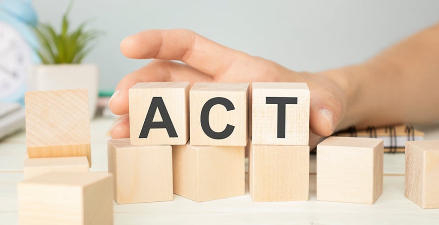 a hand with wooden blocks that spell act