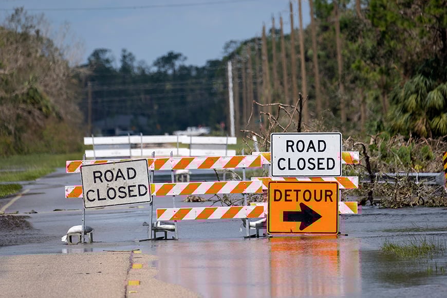 road closed signs blocking a road with a detour signpost