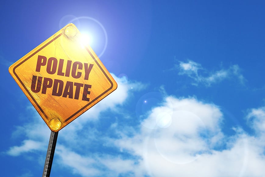 a yellow sign with the words policy update against a blue sky