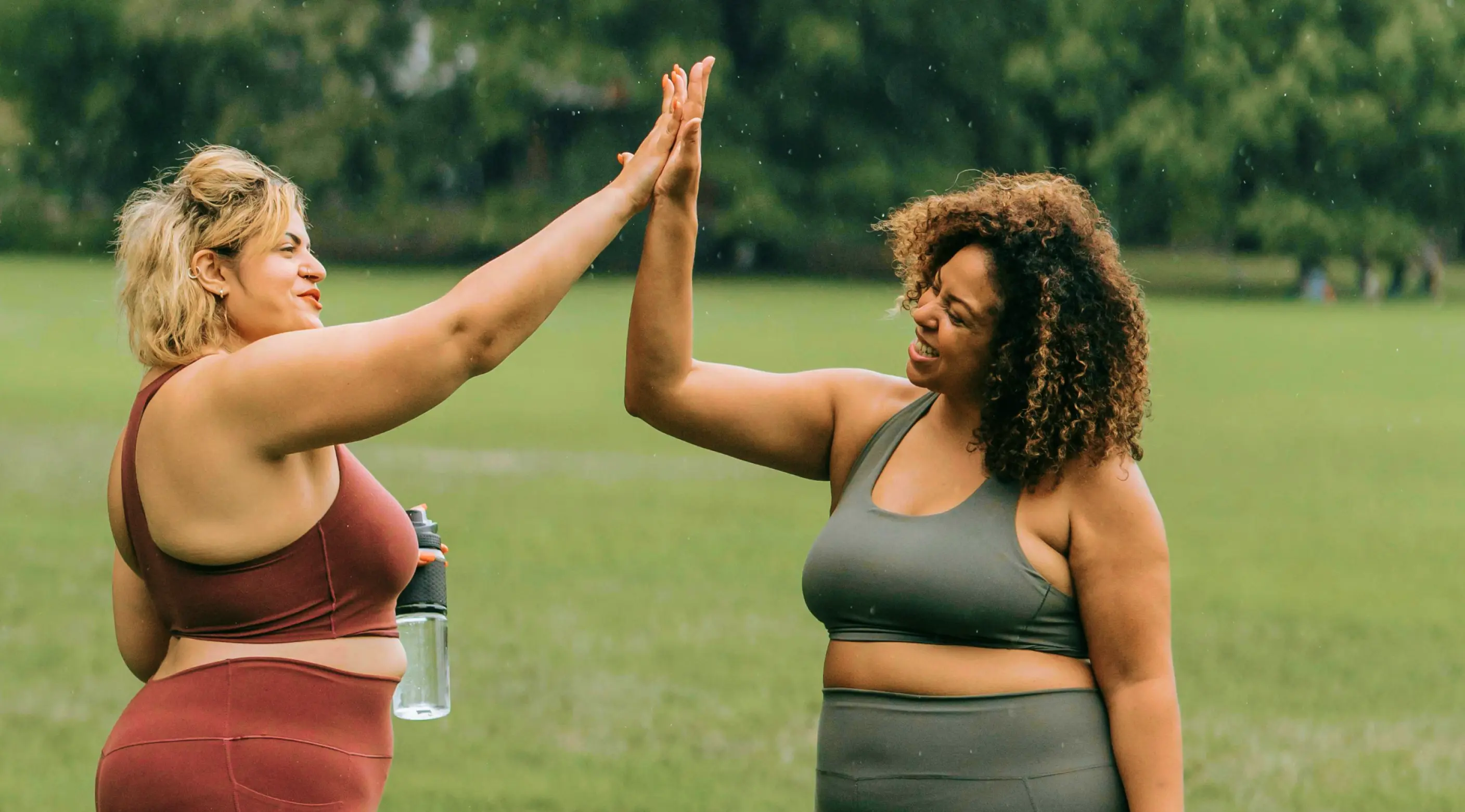 Two women high-fiving outdoors, representing clinically guided weight loss care