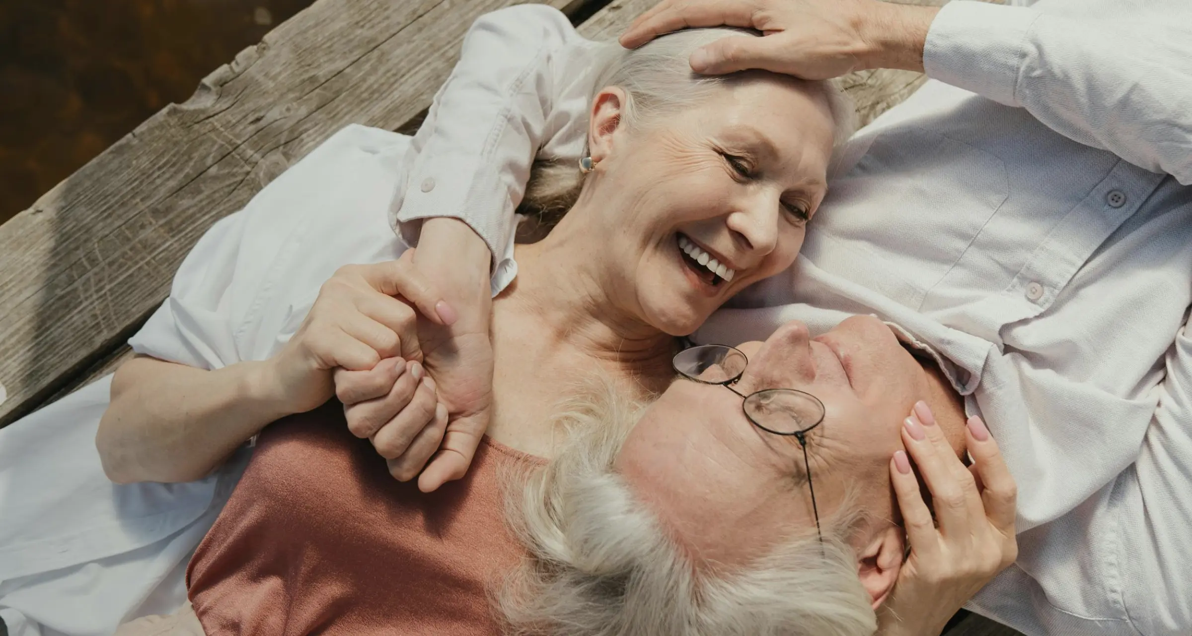 Older couple lying together and smiling, representing the next step in healthy aging care