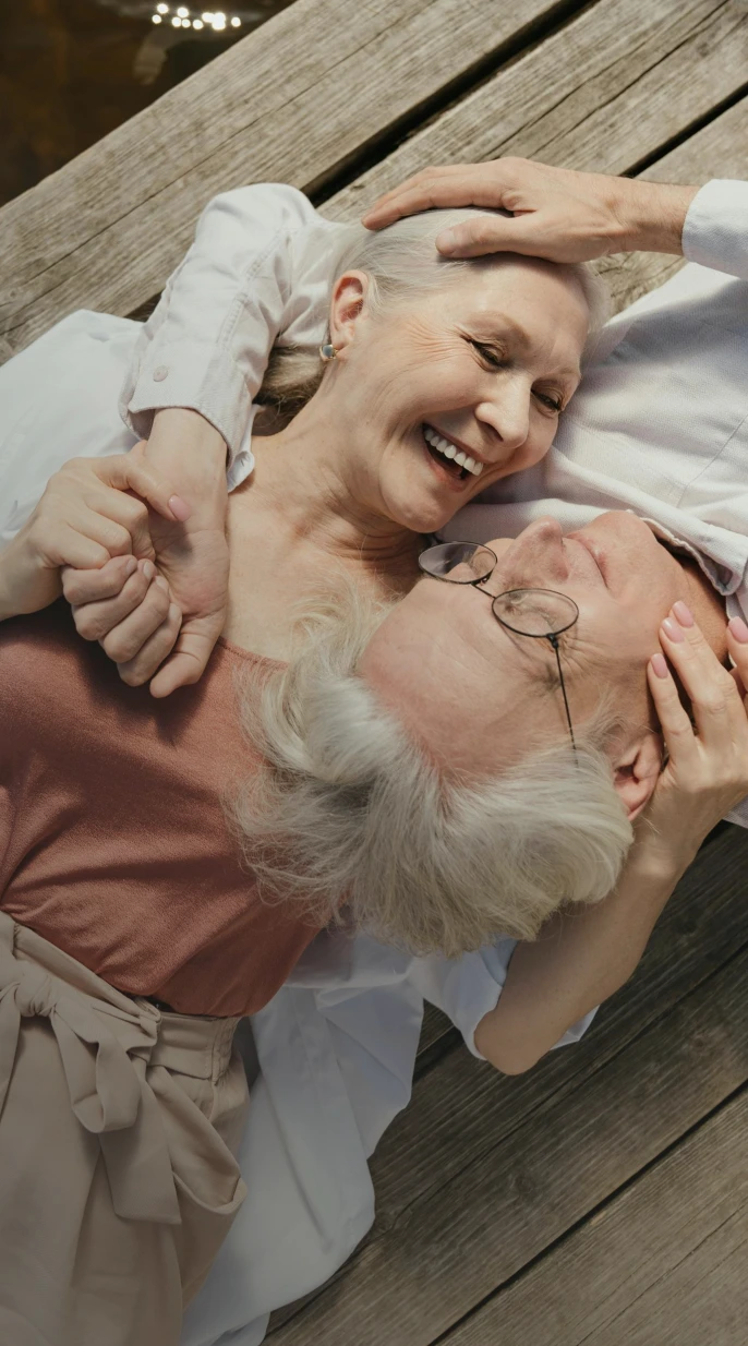 Older couple lying together and smiling, representing the next step in healthy aging care