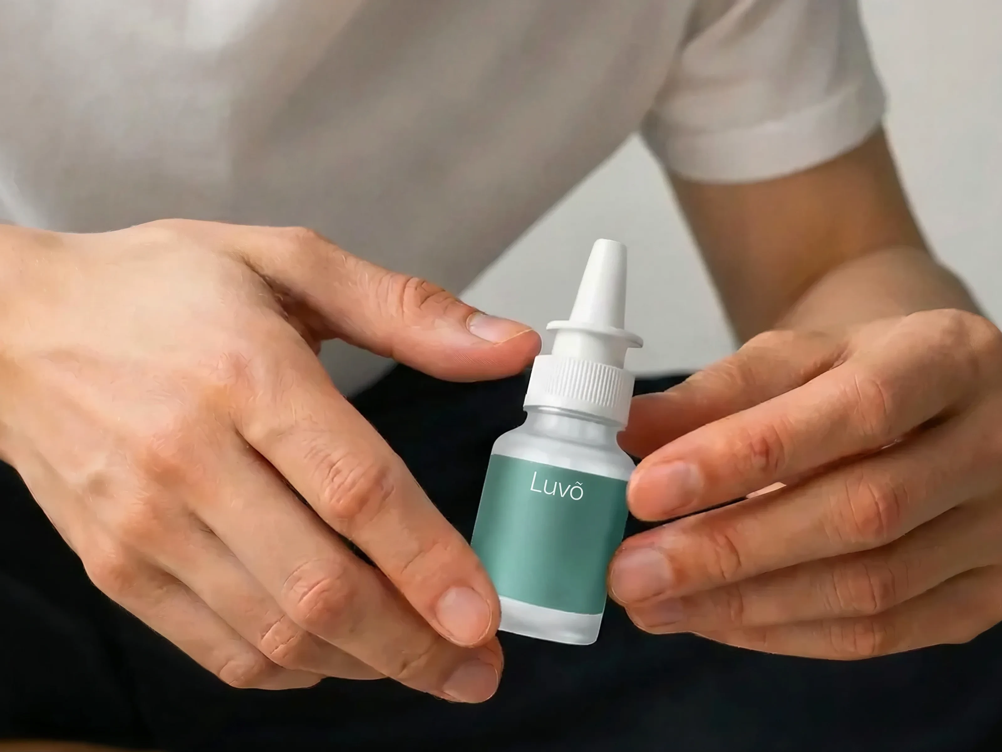 Hand holding an NAD+ nasal spray bottle