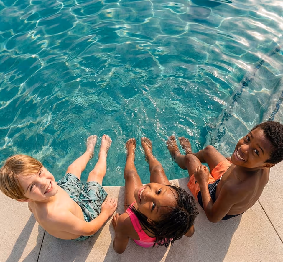 Young child with closed eyes floating relaxed on their back in a clear swimming pool wearing a patterned swimsuit.
