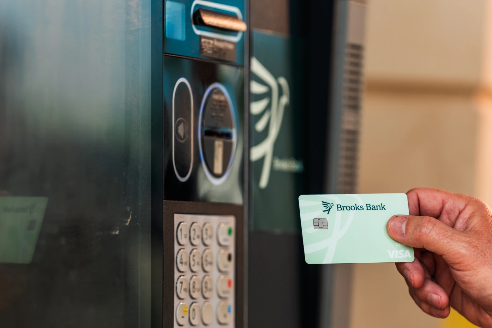 Customer inserting a Brooks Bank Visa debit card at a drive-up ATM