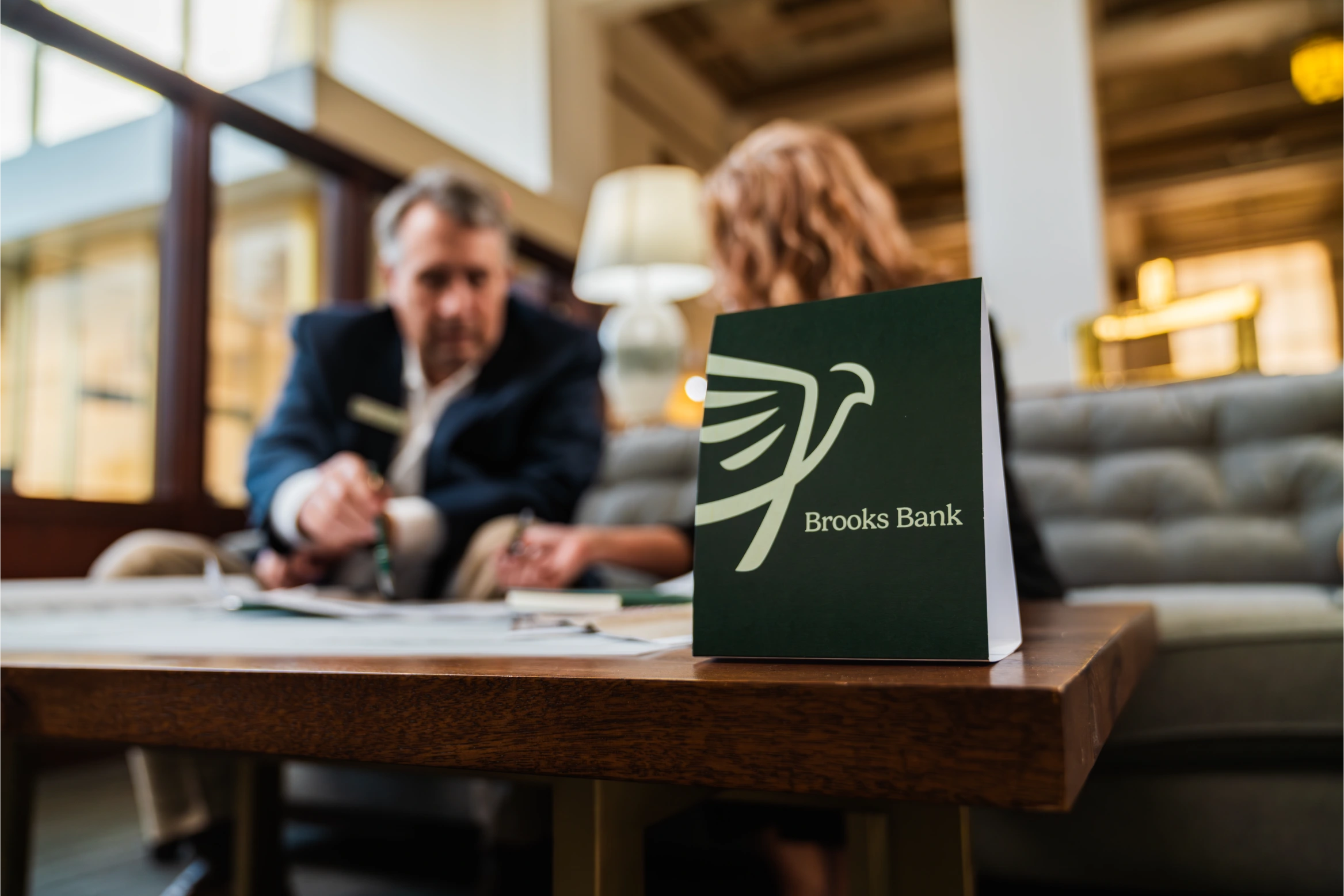 Brooks Bank tent card on a lobby table while a banker meets with a customer