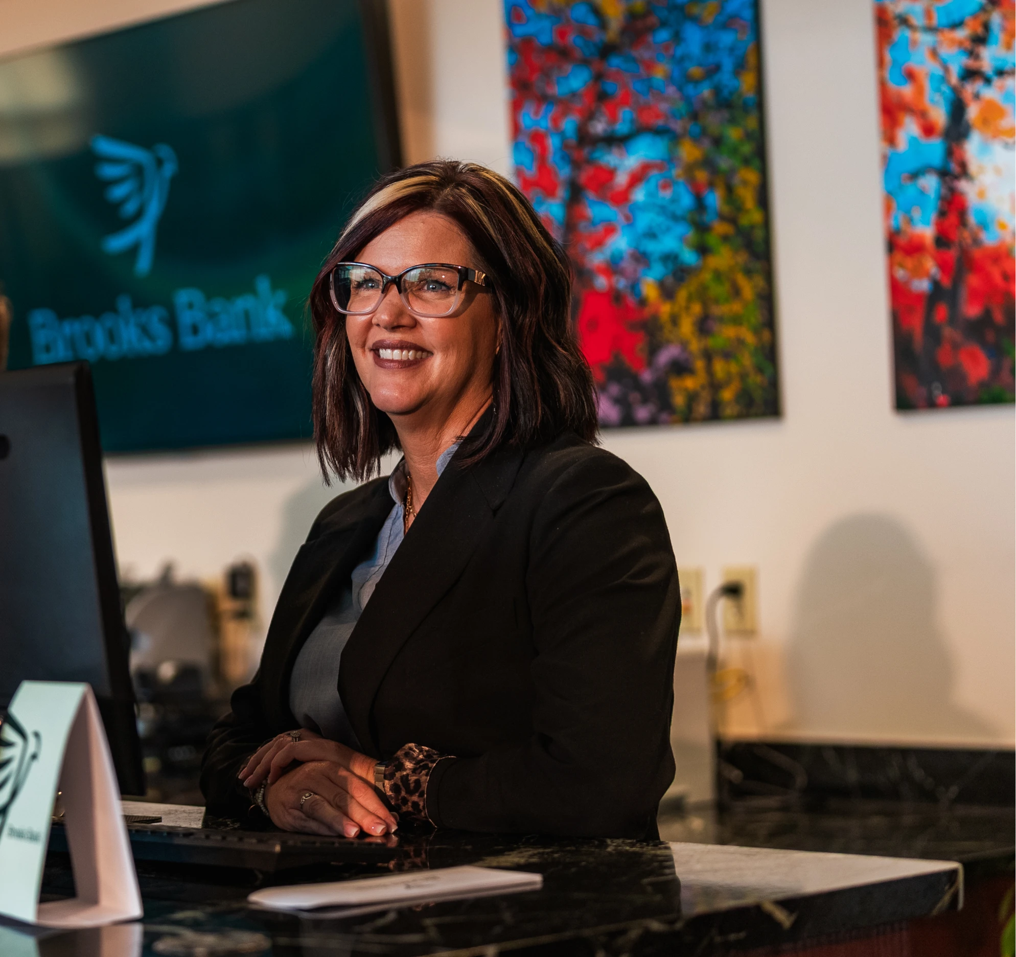 Brooks Bank banker smiling at a teller station in the branch lobby