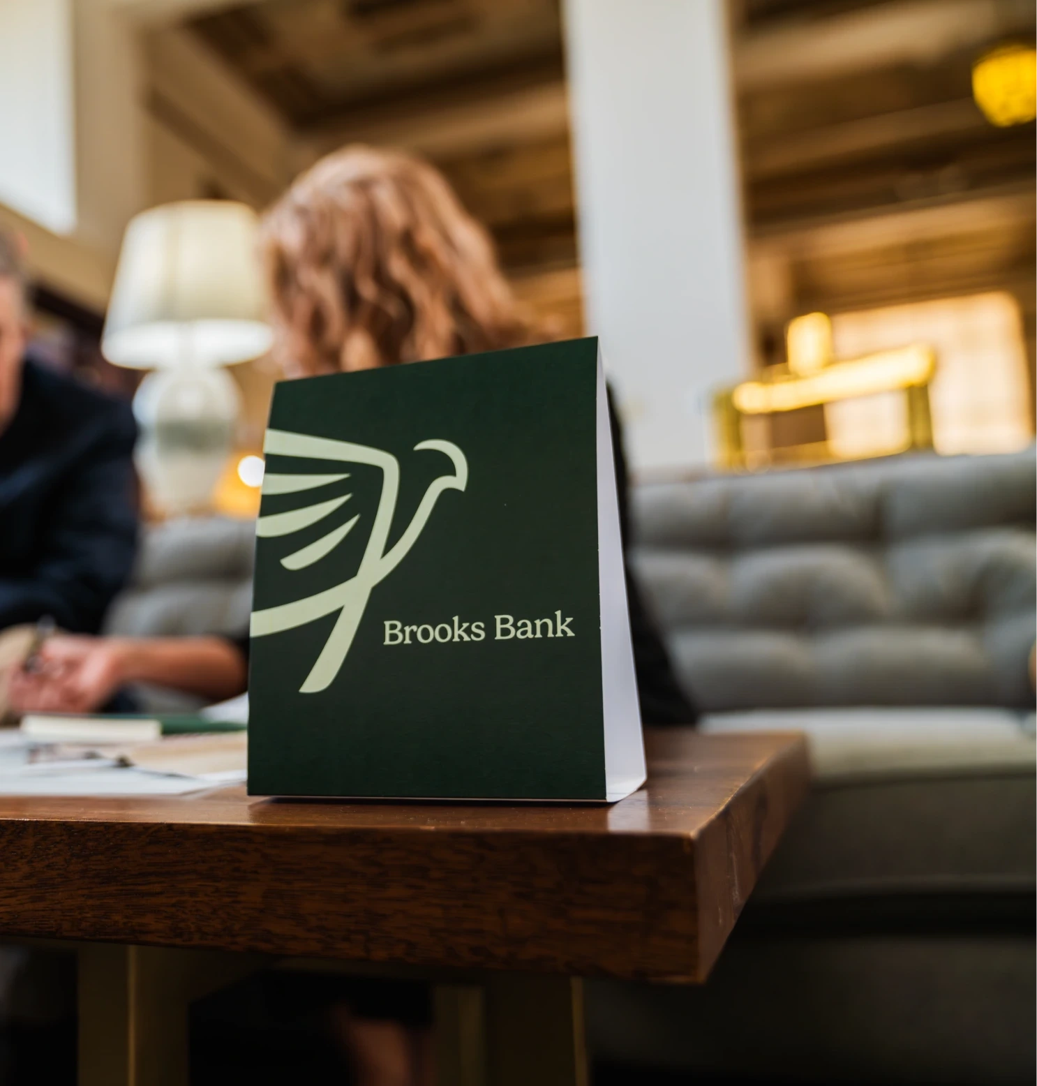 Brooks Bank tent card on a lobby table while a banker meets with a customer