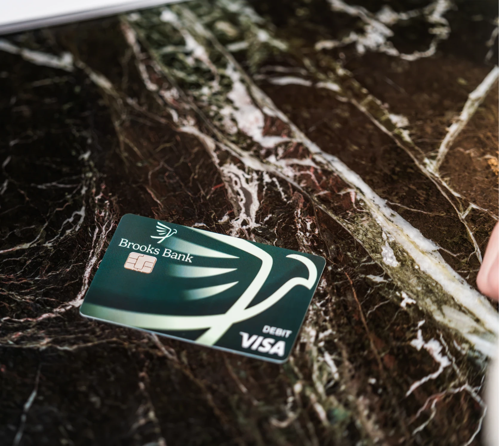 Green Brooks Bank Visa debit card lying on a marble counter