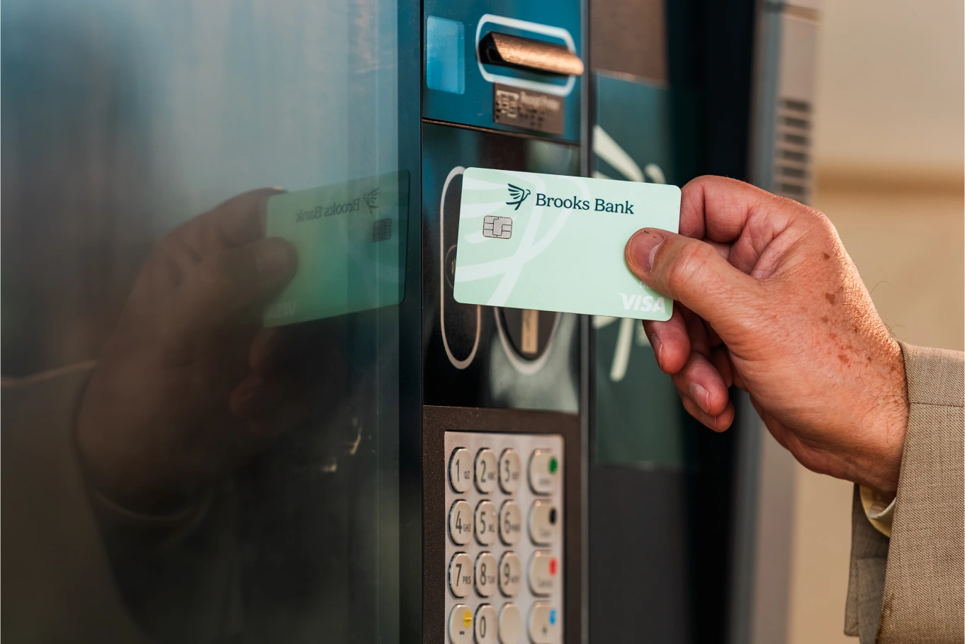 Customer tapping a Brooks Bank Visa debit card at a drive-up ATM