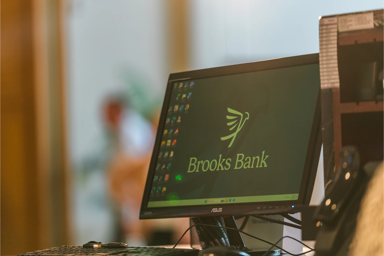 Computer monitor displaying the Brooks Bank logo at a teller station