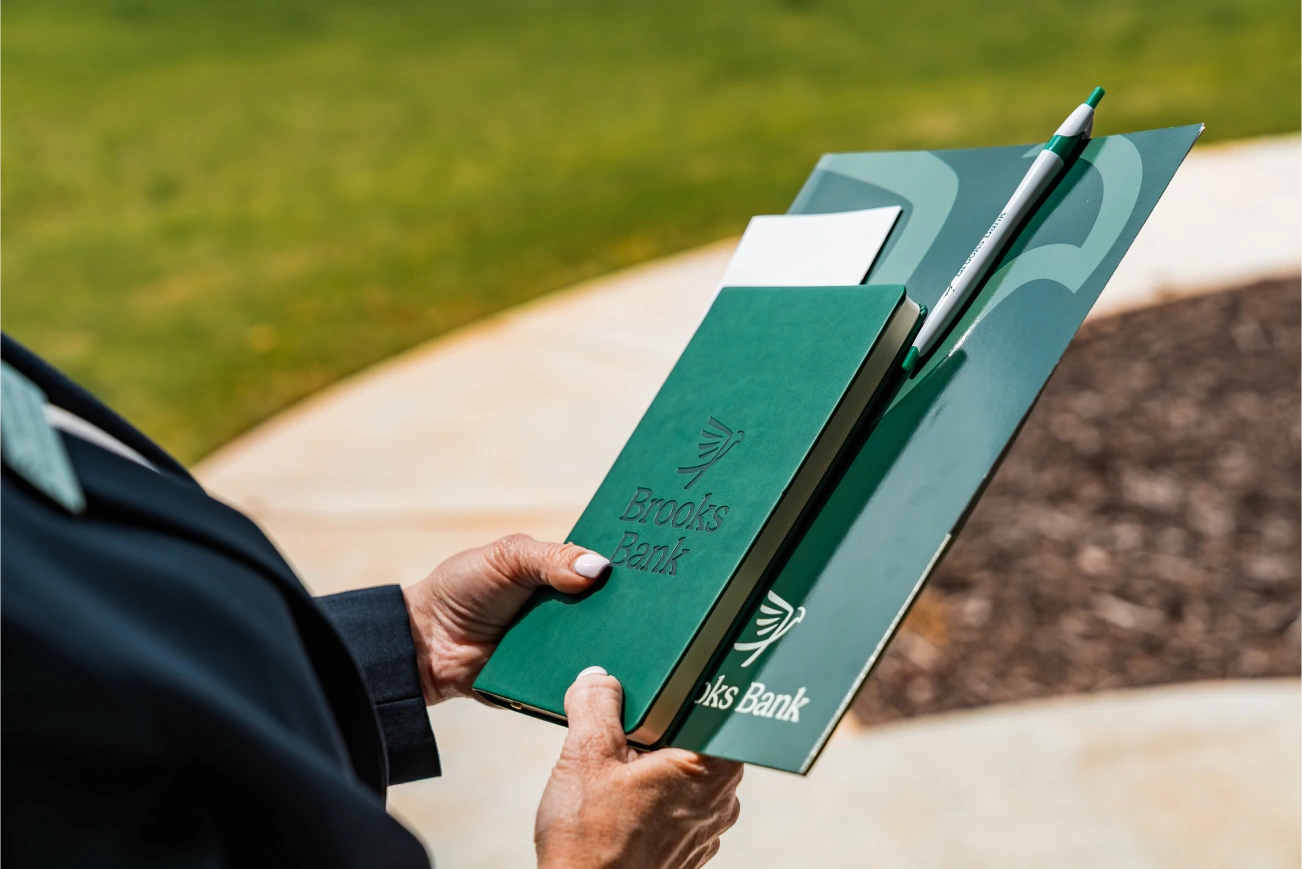 Advisor holding a Brooks Bank folder and notepad outside a client's home