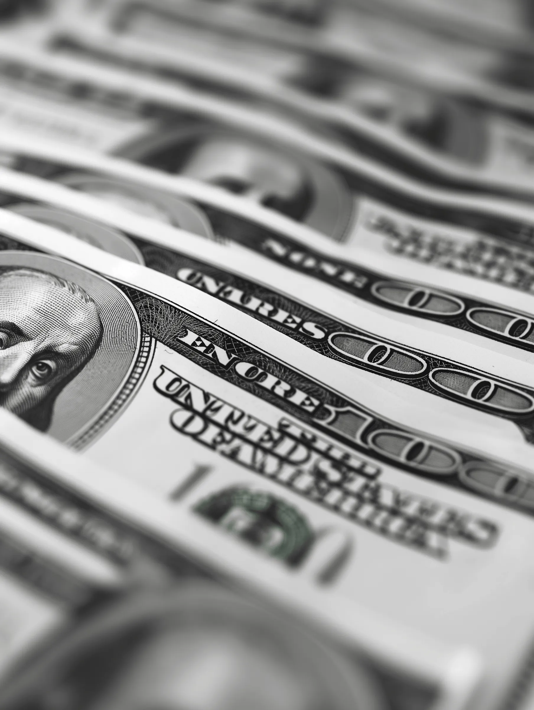 Close-up of multiple US one hundred dollar bills layered in a fanned arrangement.