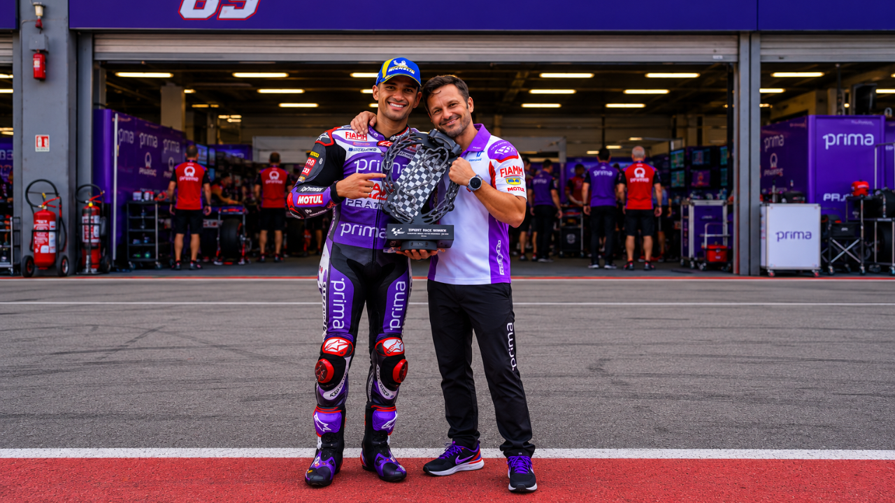 Jorge Martín e Gino Borso posano davanti al box del team con un trofeo in mano, durante un evento in circuito. 
