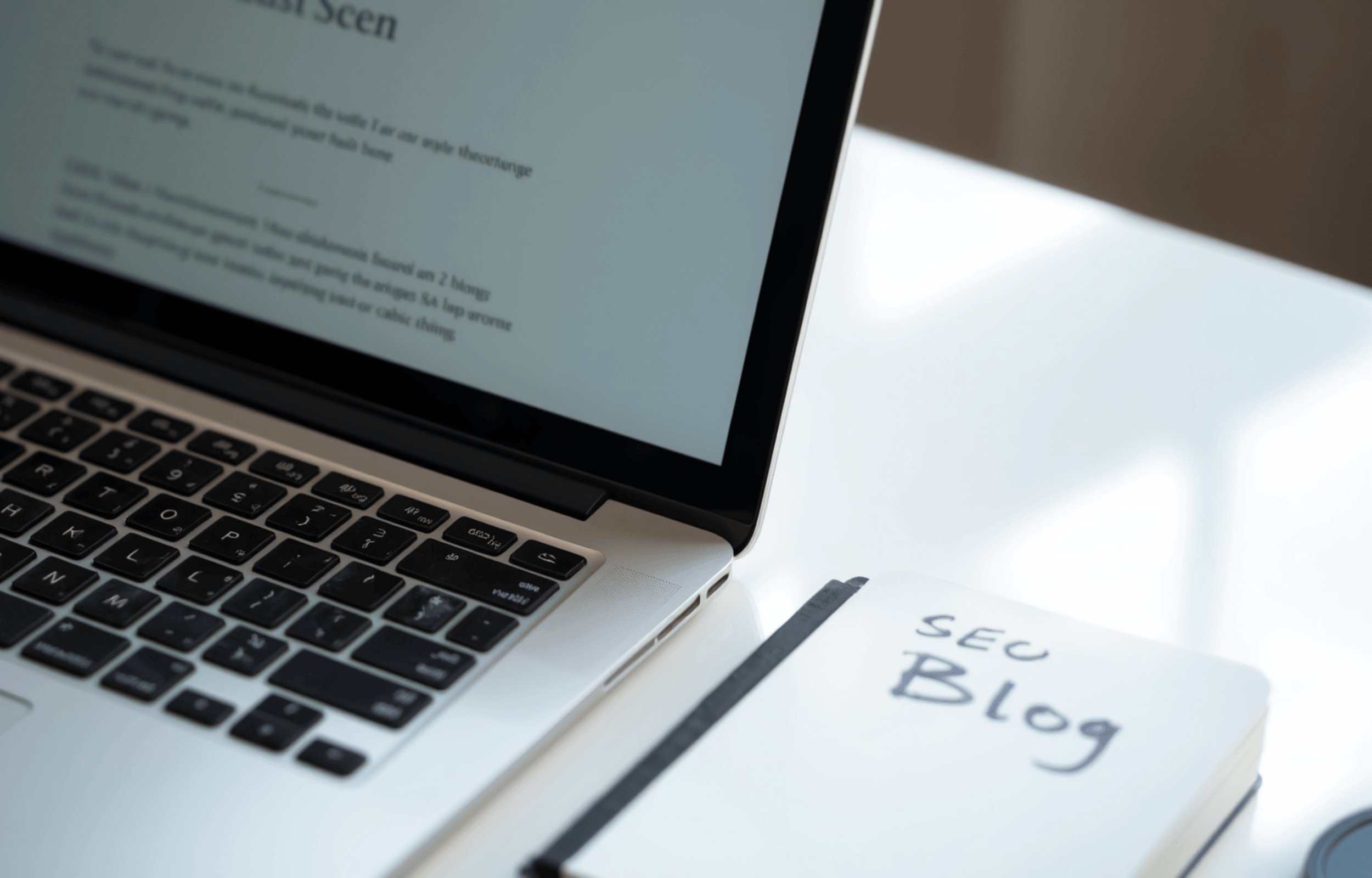 How blogging helps SEO: laptop open to a blog post on a clean white desk with a notebook showing SEO notes, natural light.