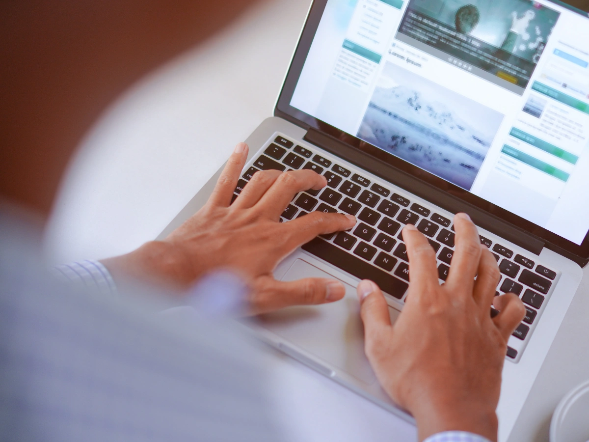 Over-the-shoulder view of a person typing on a laptop displaying a website layout with placeholder text and images.