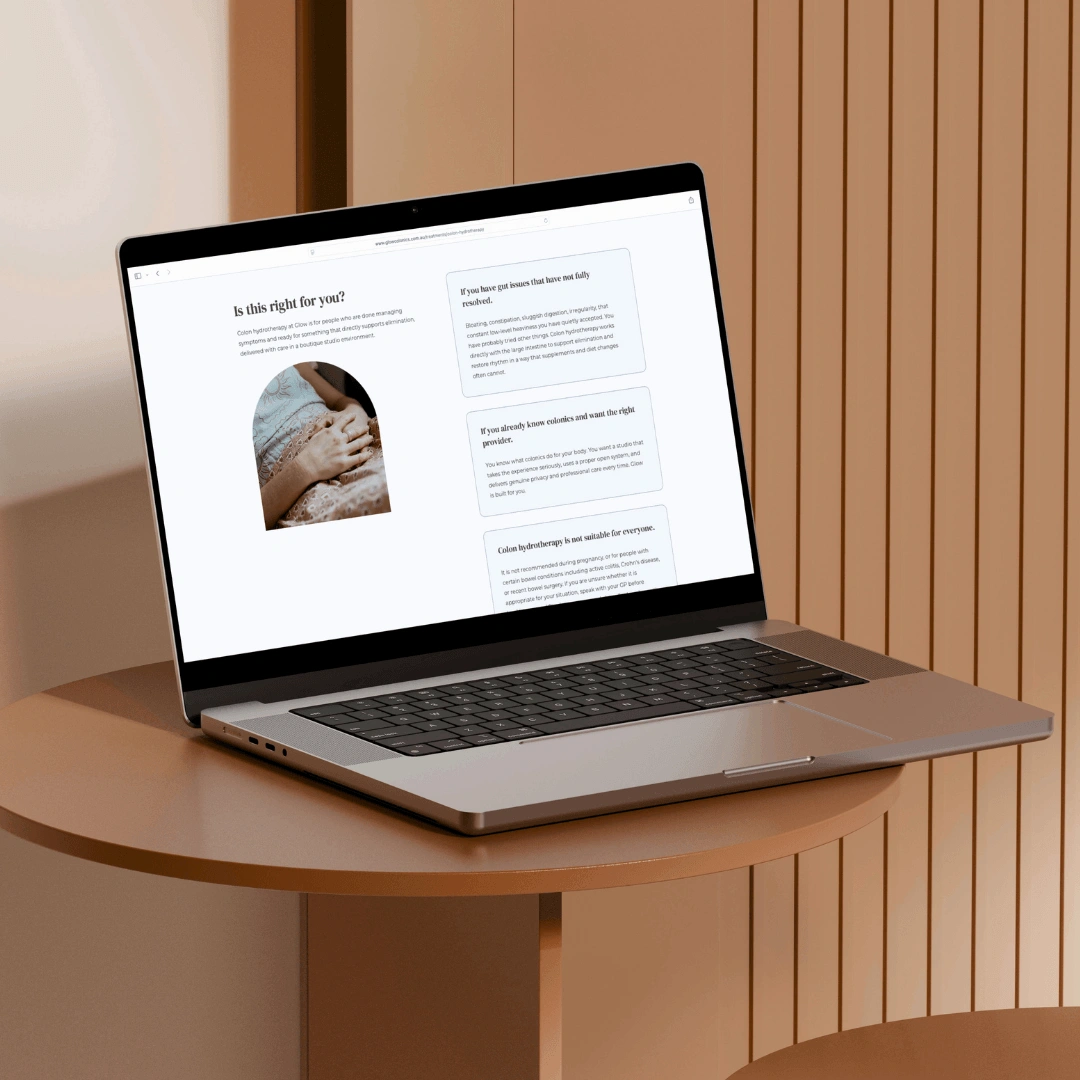 Laptop mockup on a wooden side table displaying the "Is this right for you?" section of the Glow Colonics website, outlining who colon hydrotherapy suits