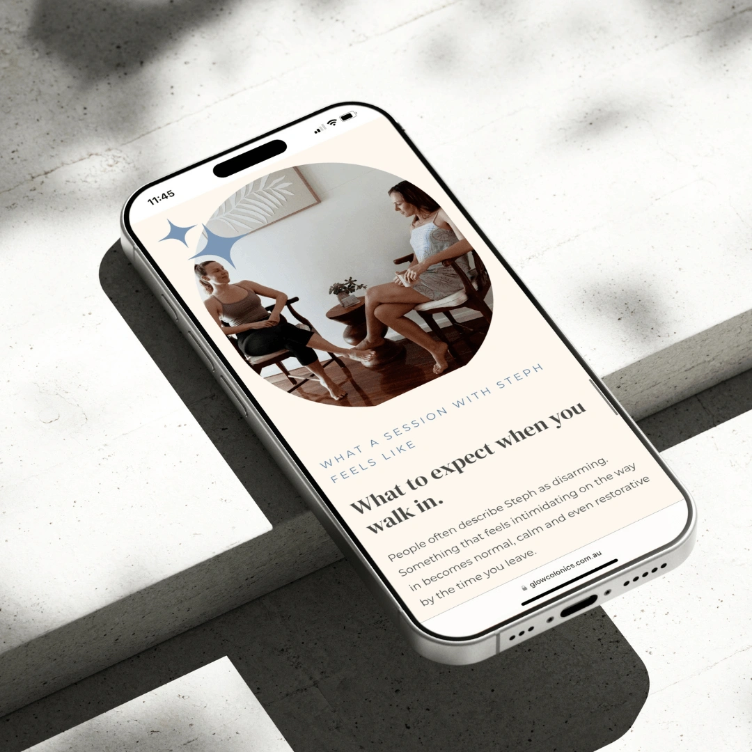 Smartphone mockup resting on a sunlit concrete step, showing the "What a session with Steph feels like" page on the Glow Colonics website