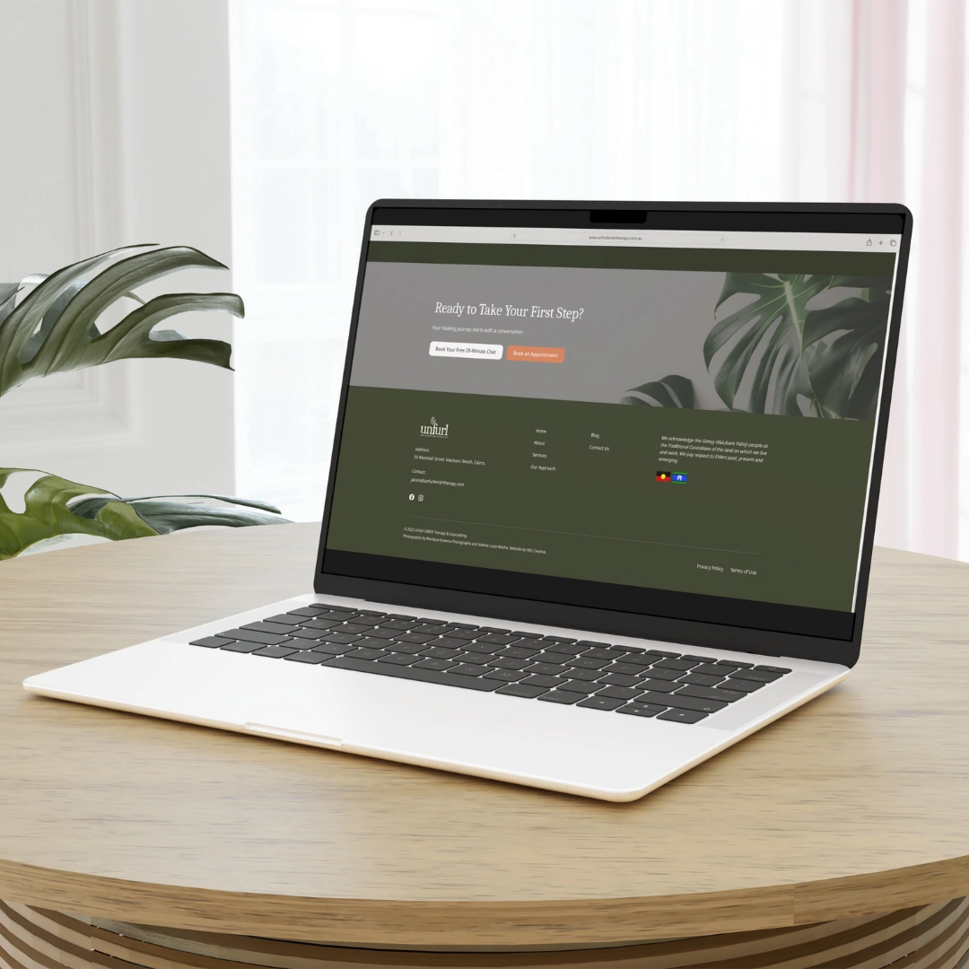 Laptop displaying the Unfurl Therapy and Counselling website on a desk beside a plant.