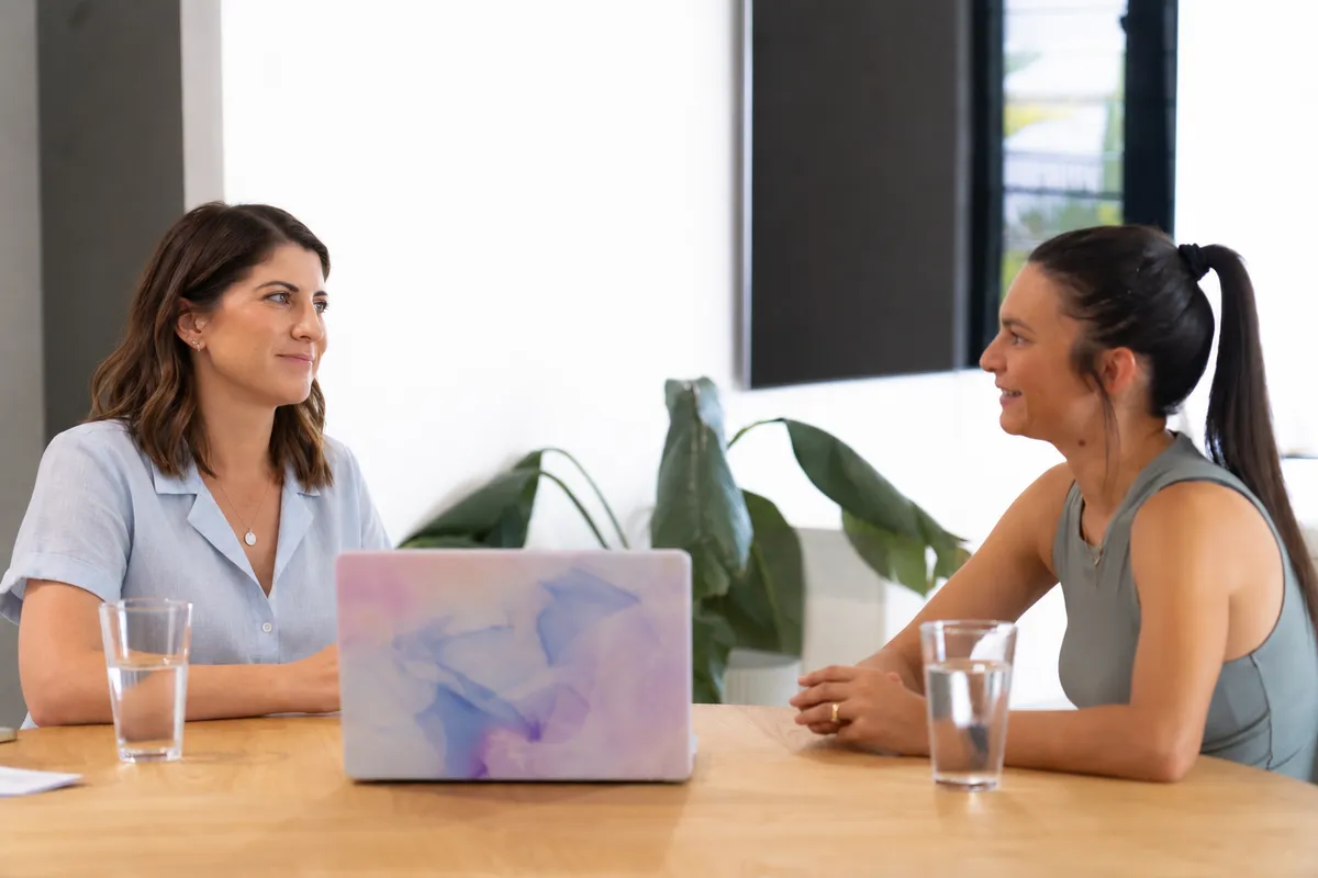 Hayley Philip and a client talking across a wooden table, with a laptop and glasses of water between them