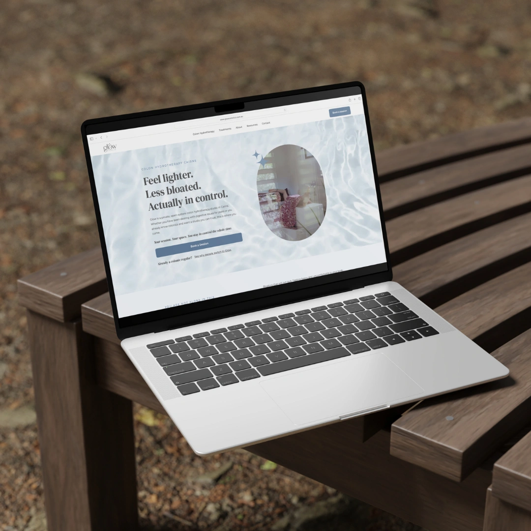 Wellness website design for Glow Colonics, homepage hero on a laptop on an outdoor timber bench, reading "Feel lighter. Less bloated. Actually in control."