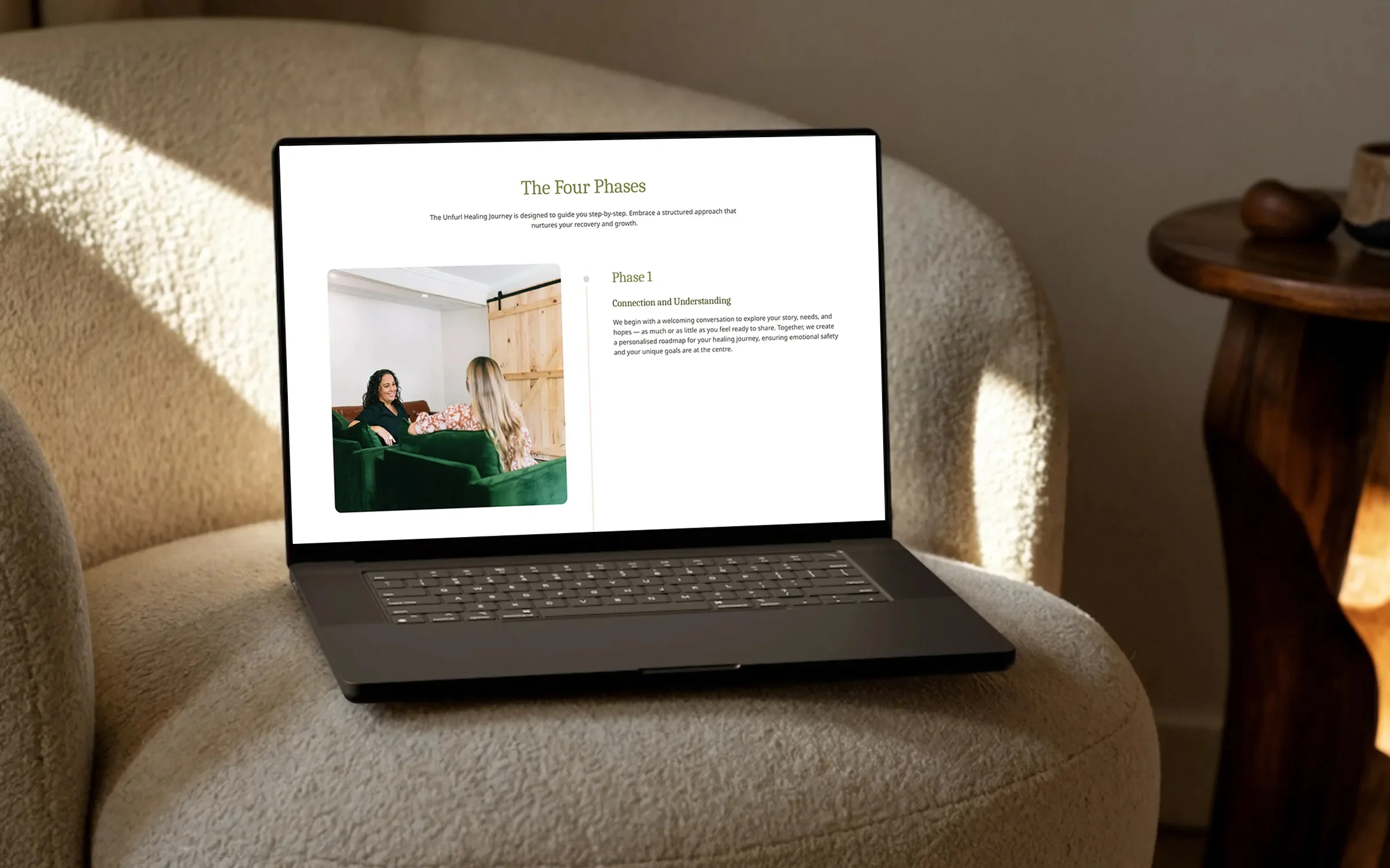 Laptop on a cream armchair showing Unfurl's 'The Four Phases' page