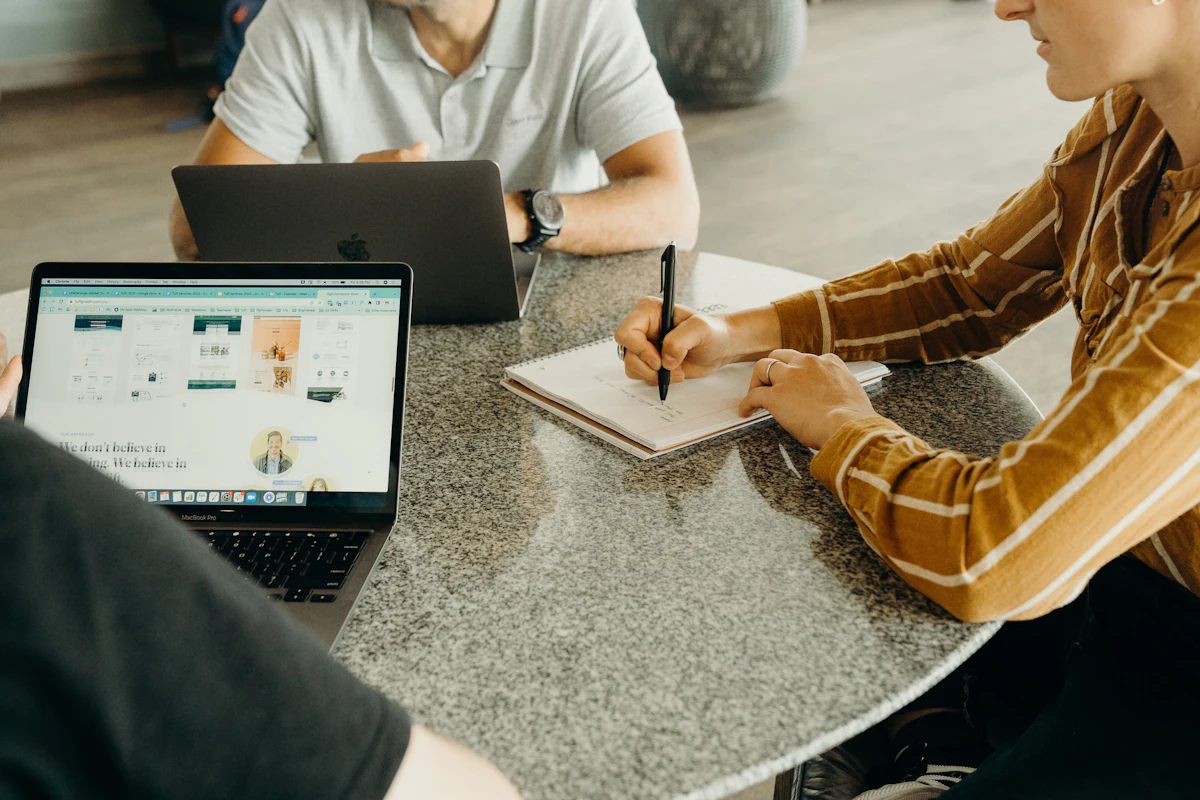 People at a table with laptops and a notebook, planning a service business website