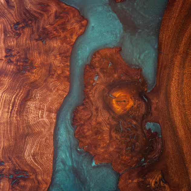 Close-up of a wooden surface with brown and reddish tones intertwined with blue resin highlights.