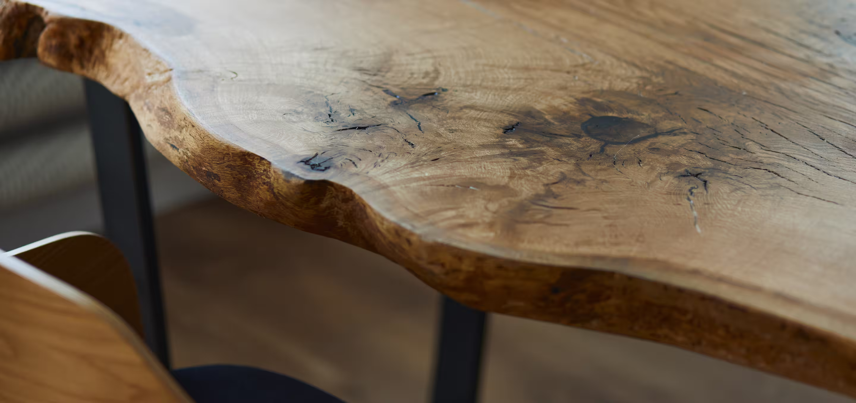 Close-up of a live edge wooden table surface showing natural grain and cracks.