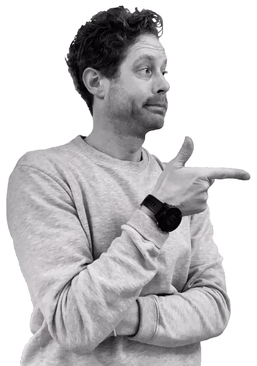 Man in gray sweatshirt with curly hair pointing to his right with a confident expression.