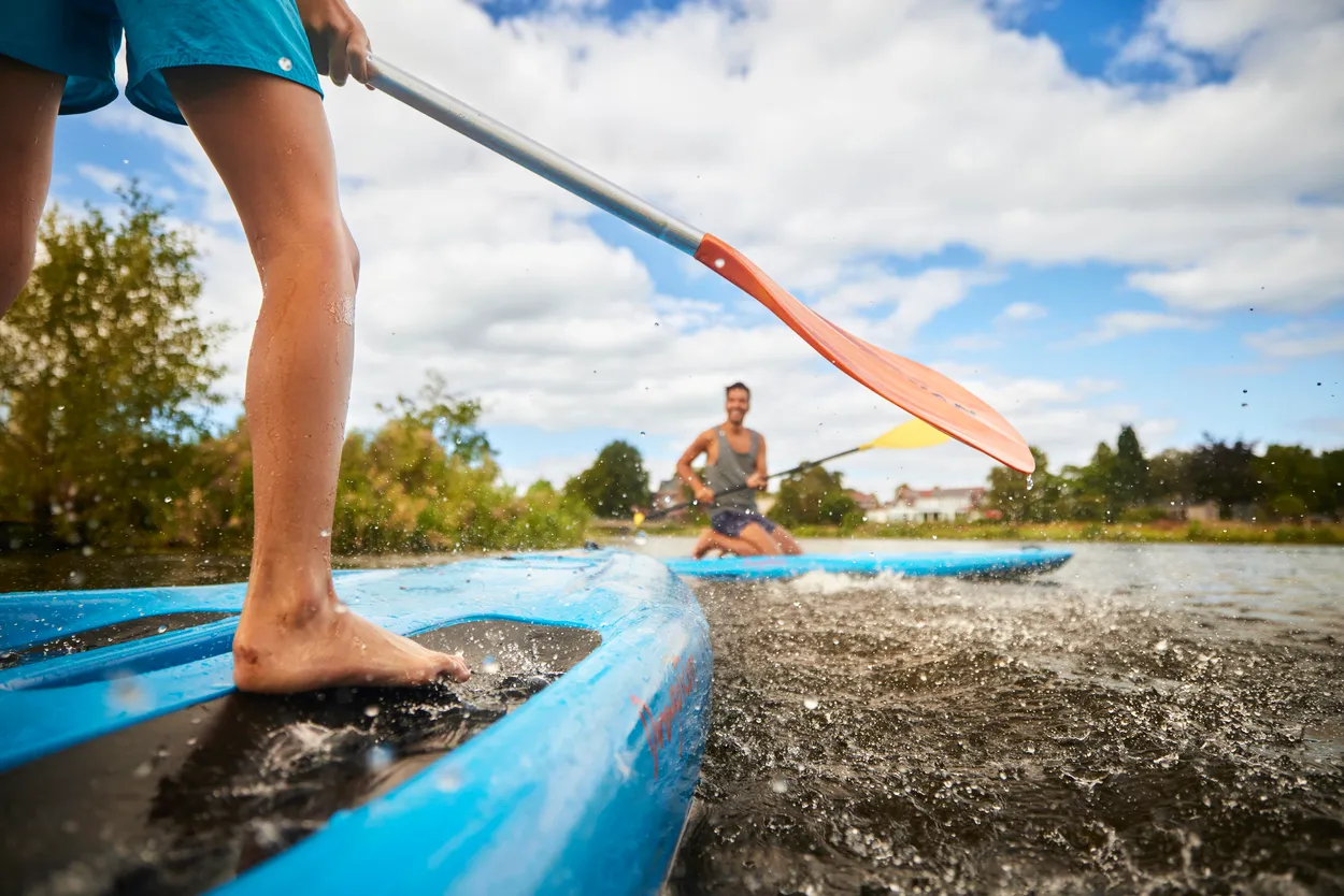 Twee mensen peddelen lachend op hun sup op de Vecht in Hardenberg.