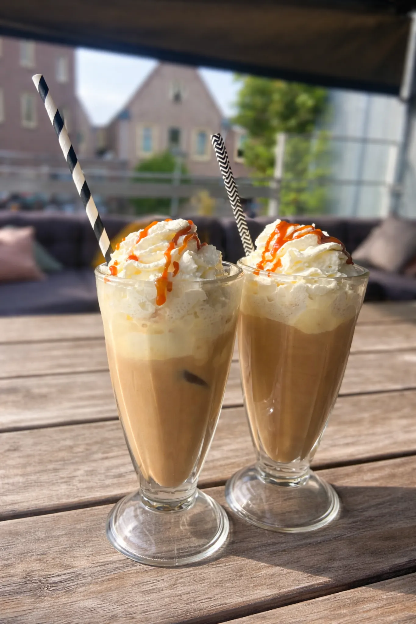 Twee glazen ijskoffie met slagroom en karamelsiroop op het terras van Outdoor Kaffee