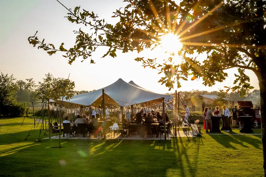 Genieten onder een grote tent met een groep mensen op een zonnige dag bij Expedition Outdoor