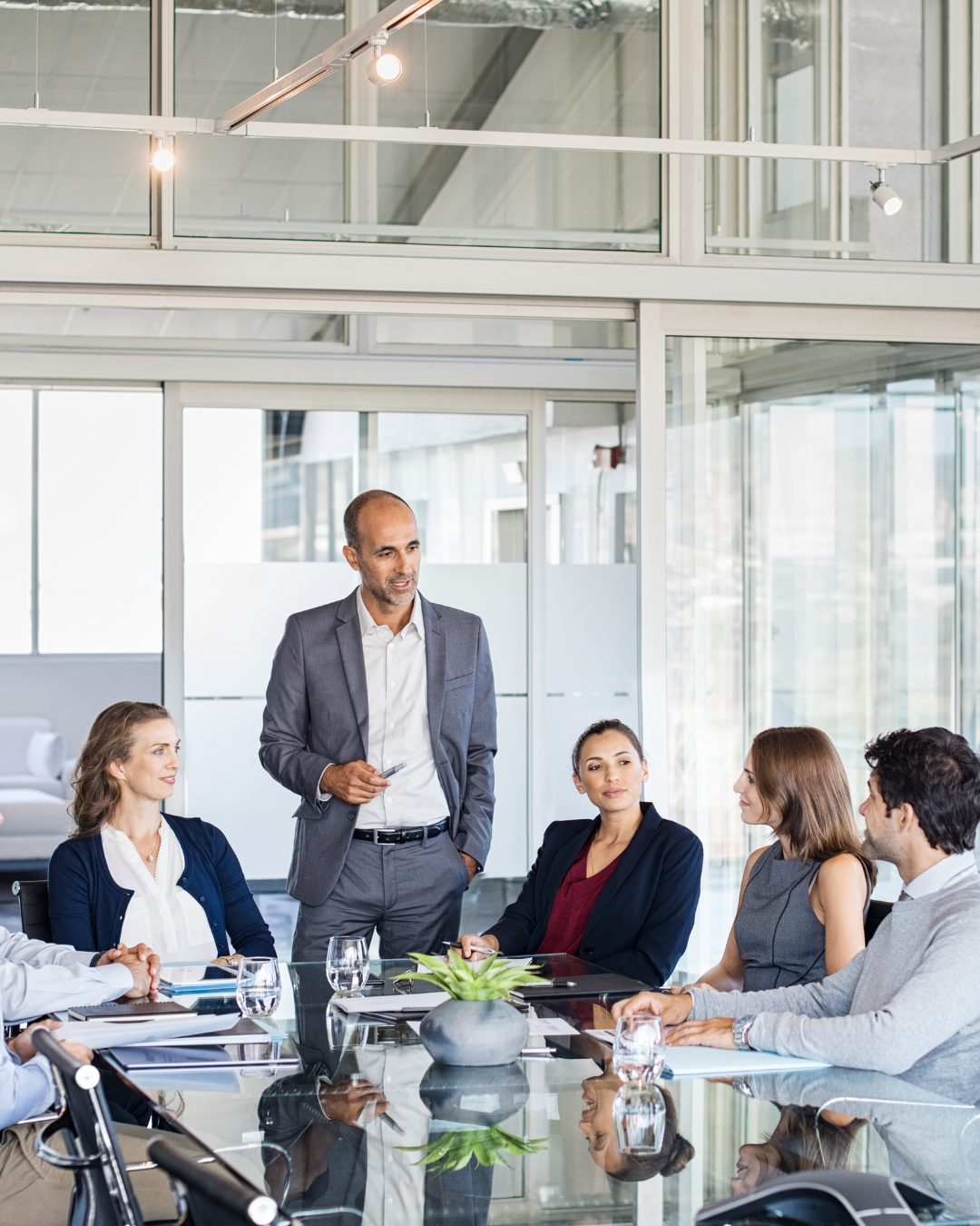People sitting at a table writing notes in a notebook during a meeting.